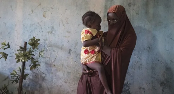 Une femme en niqab portant un enfant dans ses bras.
