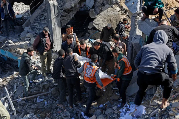 Secouristes transportant un corps dans les décombres à Gaza après des frappes israéliennes.
