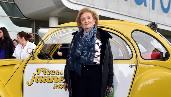 Bernadette Chirac lors d'un événement de l'opération Pièces Jaunes, devant la voiture emblématique de la campagne.