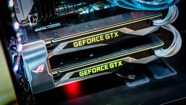 Deux cartes graphiques Nvidia GeForce GTX 1080 en configuration SLI, illuminées et connectées.