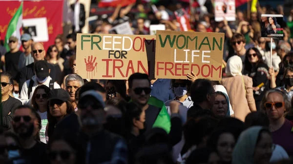 Manifestation à Montréal en soutien aux femmes iraniennes, avec des pancartes 'FREEDOM FOR IRAN' et 'WOMAN LIFE FREEDOM'.