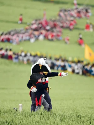 Participants en costumes d'époque lors de la reconstitution de Waterloo, l'un pointant, l'autre observant à la lunette.