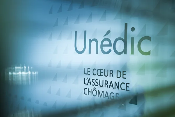 Siège de l'Unédic : le logo et le slogan de l'organisme visibles sur une porte vitrée.