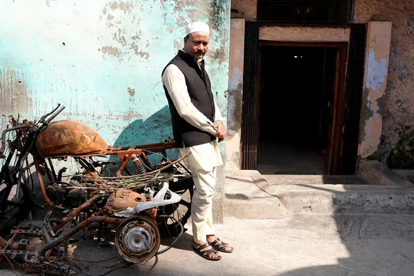 Un homme près d'une moto calcinée devant un bâtiment délabré à Haldwani, Inde.