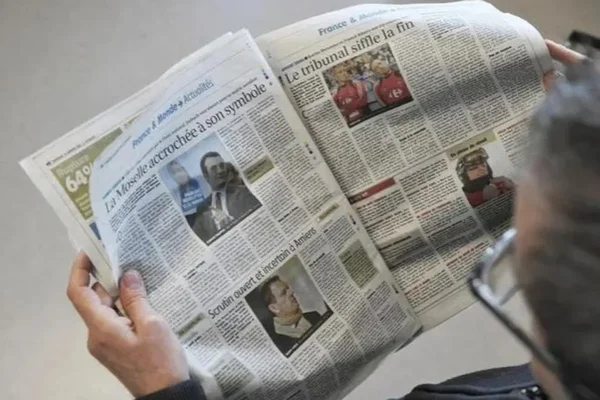 Un lecteur parcourt un journal d'actualités, contexte de la grève au Monde.