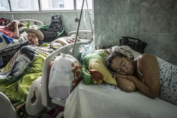 Salle d'hôpital surpeuplée au Venezuela, montrant des patients dans des lits.