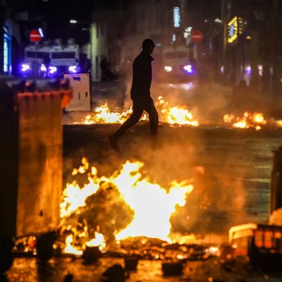 Scène d'émeute nocturne en Irlande du Nord avec incendies et débris.