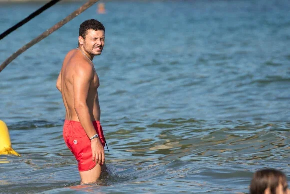 Kev Adams a pris du poids 'extrêmement vite' : photographié torse nu en maillot rouge dans l'eau.