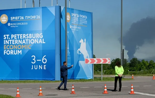 Un participant photographie le panneau du Forum économique international de Saint-Pétersbourg, tandis que la fumée de l'attaque s'élève au loin.