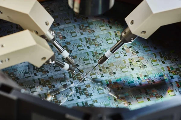 Tranche de silicium contenant des circuits intégrés en cours de test par des pointes de palpage.