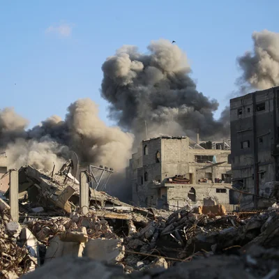 Destruction massive à Gaza après des frappes israéliennes, avec des immeubles en ruine et de la fumée s'élevant dans le ciel.