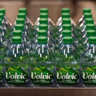 Bouteilles Volvic avec bouchons verts alignées sur une palette, étiquette ornée d'un volcan.