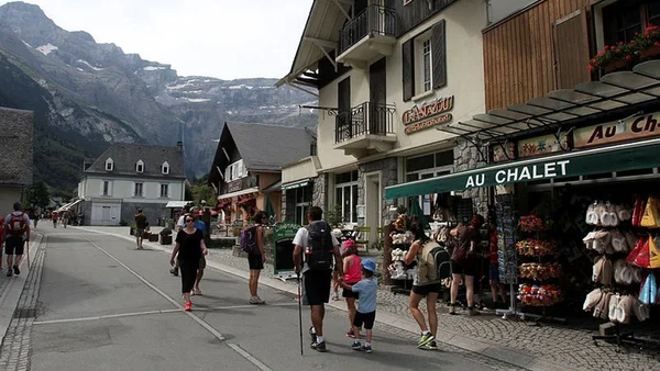 Promenade dans un village de montagne typique des Pyrénées, avec commerces et piétons.
