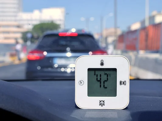Thermomètre indiquant 42 °C à l'intérieur d'une voiture en ville.