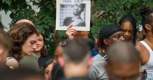 Rassemblement public avec une photo d'O'Shae Sibley brandie par un participant.
