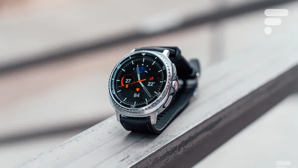 Samsung Galaxy Watch sur une rambarde, cadran avec données météo et cardiaques.