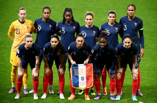 Photo d'avant-match des Bleues lors de l'Euro féminin 2022, avec un fanion commémoratif au premier plan.