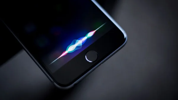 Un smartphone affichant l'interface de Siri avec son animation de formes d'onde.