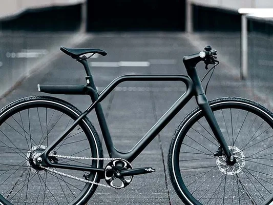 Vélo électrique noir mat au design intégré, garé sur une surface pavée.