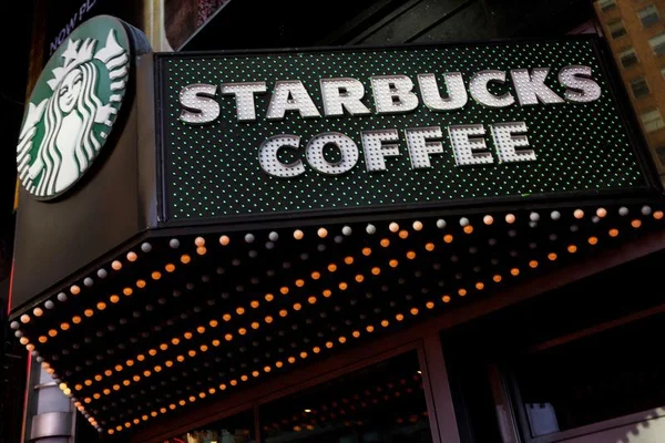 Enseigne d'un café Starbucks illuminée la nuit.