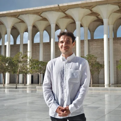 Christophe Gleizes souriant devant un bâtiment à colonnades.