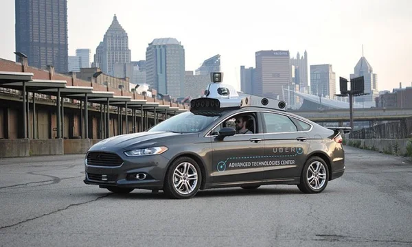 Ford Fusion autonome du centre de technologies avancées d'Uber, garée avec un conducteur à bord.
