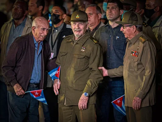 Ramiro Valdés, entouré de deux hommes, lors d'un rassemblement public à Cuba.
