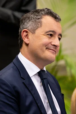 Gérald Darmanin, souriant, dans un décor extérieur.