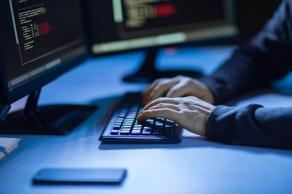 Mains tapant sur un clavier devant des écrans de code, illustrant une cyberattaque.