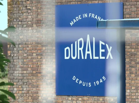 Panneau historique Duralex sur un mur de briques, rappelant l'origine française de la marque depuis 1945.