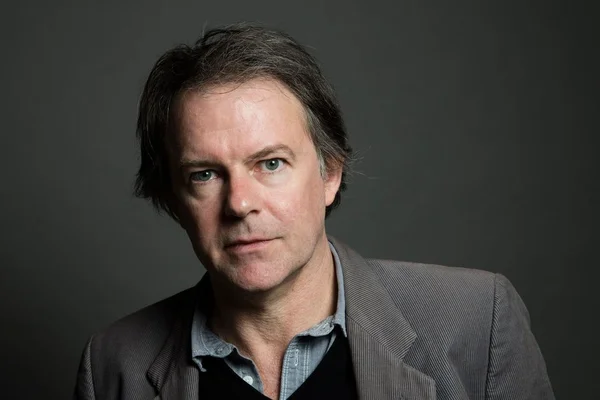 Yannick Haenel en studio, veste grise et regard direct.