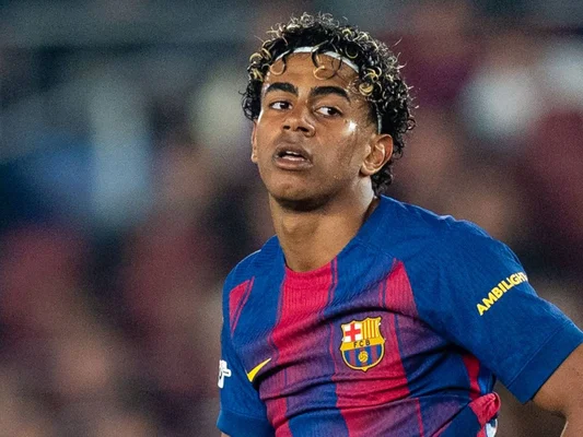 Lamine Yamal sous le maillot du FC Barcelone, en pleine action lors d'un match, avec un bandeau blanc.