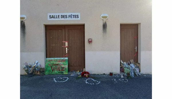 La salle des fêtes de Crépol, marquée par des traces de brûlure, avec un hommage floral et des messages devant l'entrée.