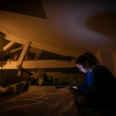 Un adolescent utilise son smartphone dans une chambre sombre éclairée par l'écran.