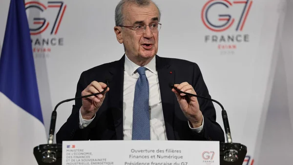 François Villeroy de Galhau lors d'une conférence de presse officielle, avec les drapeaux français et le logo G7 France.