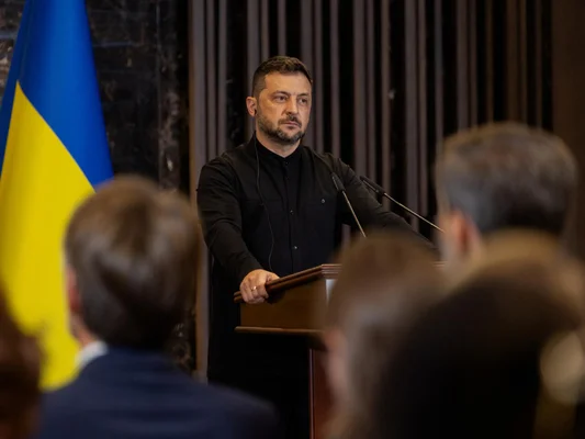 Volodymyr Zelensky lors d'une conférence de presse, drapeau ukrainien en arrière-plan.