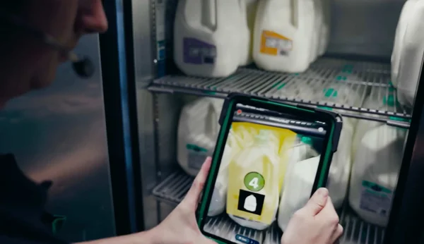 Employé utilisant un outil IA d'inventaire en réalité augmentée dans un réfrigérateur Starbucks.