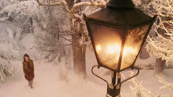 Scène du film Narnia : une jeune fille dans une forêt enneigée devant un réverbère illuminé.