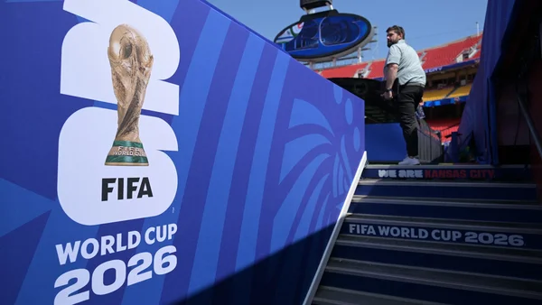 Personne dans un stade à côté du logo de la Coupe du monde 2026, évoquant l'organisation de l'événement à Toulouse.
