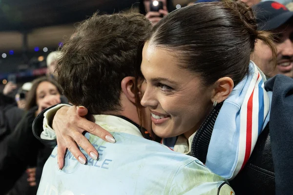Iris Mittenaere et Antoine Dupont s'enlaçant au Stade de France, entourés de photographes.
