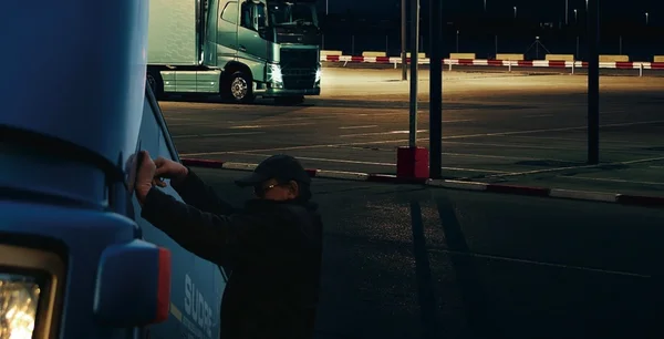 Personne s'affairant sur un camion bleu la nuit.