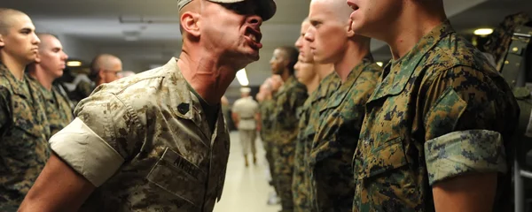 Instructeur militaire réprimandant une recrue lors d'un entraînement en caserne.