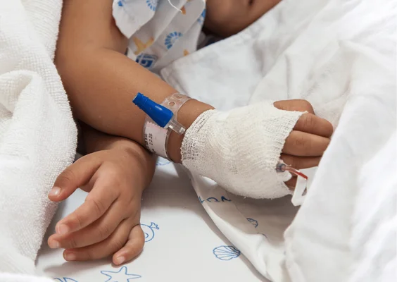 Bras d'un enfant hospitalisé avec perfusion intraveineuse au poignet.