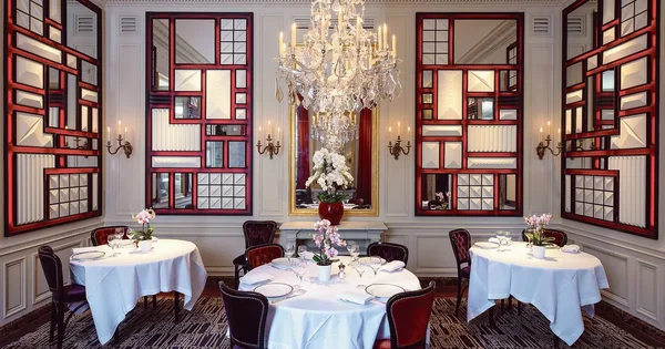 Intérieur du restaurant L'Ambroisie : salle à manger élégante au lustre en cristal.