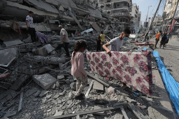 Des Palestiniens inspectent les ruines de la tour Aklouk détruite par des frappes israéliennes à Gaza, le 8 octobre 2023.