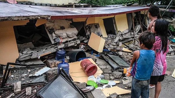 Des habitants au milieu des ruines d'un bâtiment effondré après le séisme.