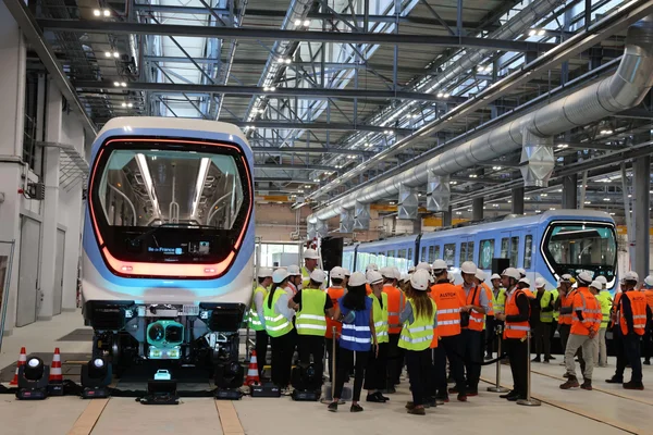 Inspection de rames de métro du Grand Paris Express dans un hall de maintenance.