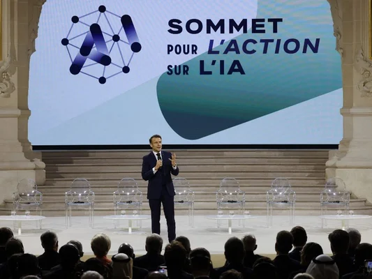 Orateur au Sommet pour l'action sur l'intelligence artificielle à Paris, devant un écran géant.