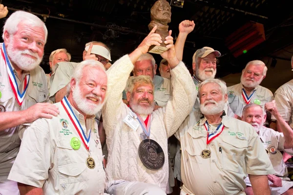 Concours de sosies d'Ernest Hemingway : participants barbus en chemises beiges avec médailles et trophée.