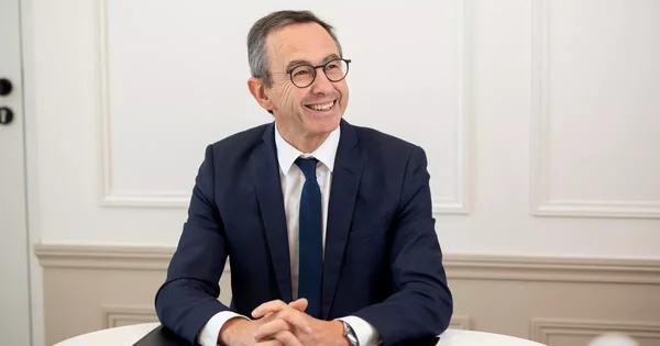Bruno Retailleau, souriant, assis à une table blanche.